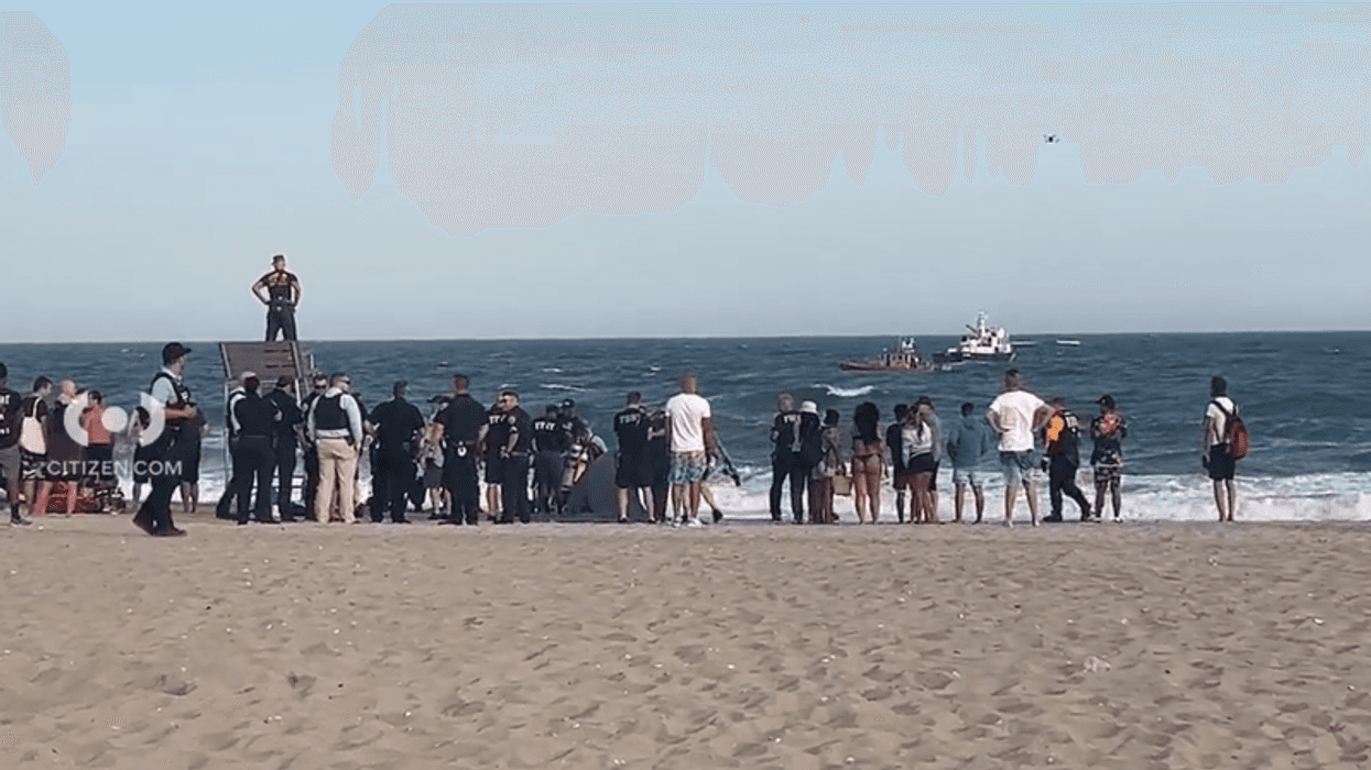 Police and beachgoers observe official sea vessels searching for two missing teen swimmers at Jacob Riis Park in Queens on June 21.