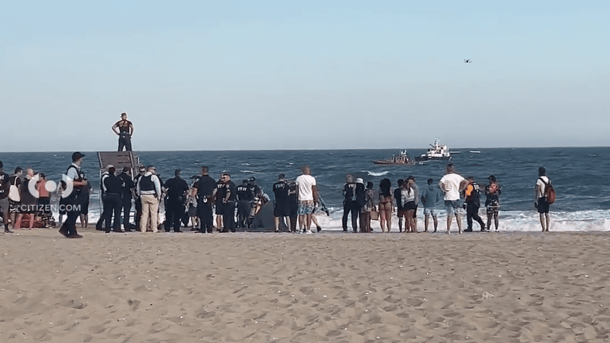 Police and beachgoers observe official sea vessels searching for two missing teen swimmers on Friday night at Jacob Riis Park in Queens.