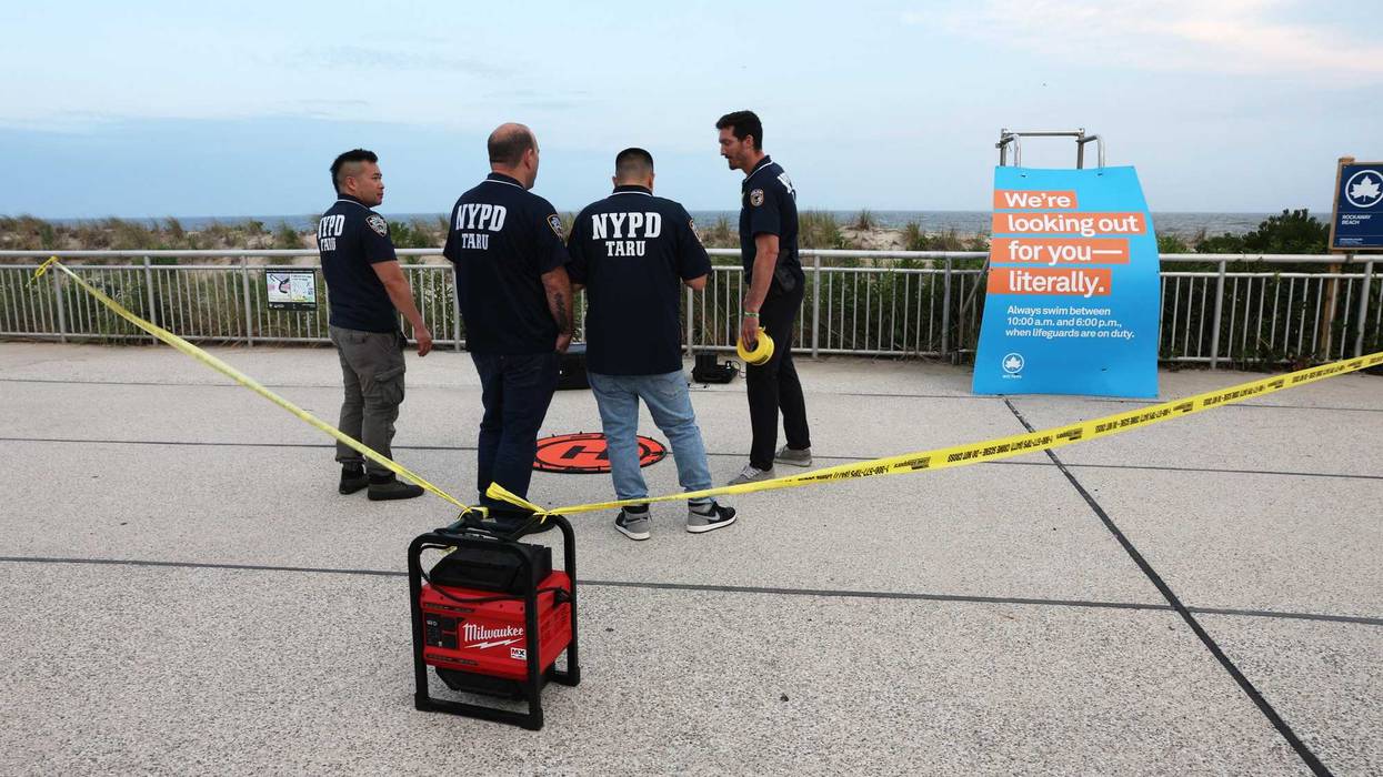 Police gather along Rockaway Beach at Beach 59th Street after a woman was attacked by a shark in the early evening on Aug. 7, 2023