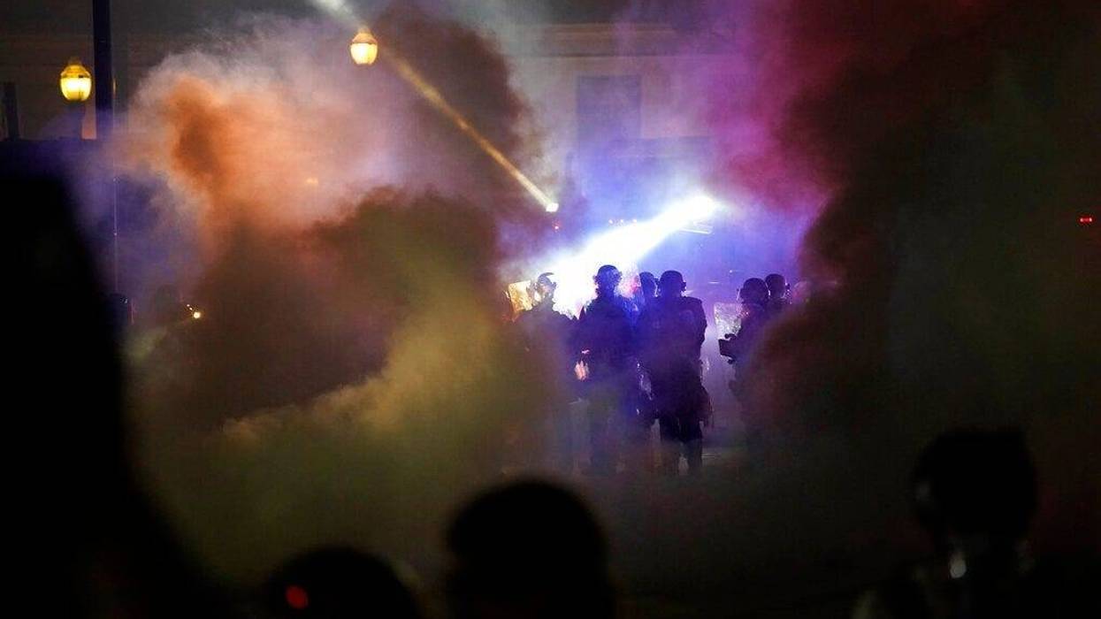 Police in riot gear clear the area in front of Kenosha County Courthouse during clashes with protesters late Tuesday, Aug. 25, 2020, in Kenosha, Wis.