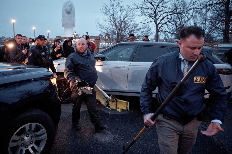 Police officers carry parts of a crashed helicopter on April 10, 2025 in Jersey City