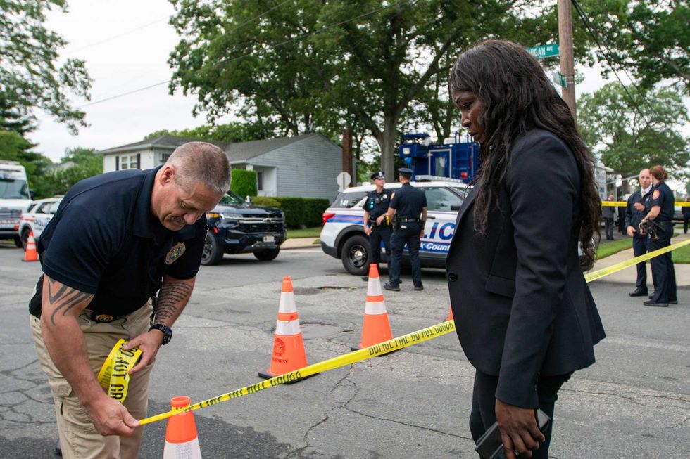 Police officers secure the area near the house where a suspect has been taken into custody on New York