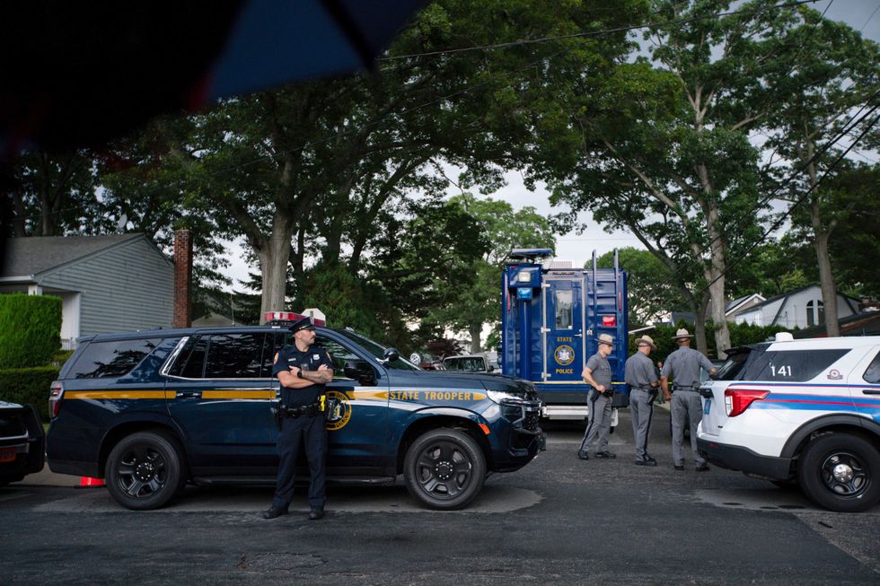 Police officers stand guard near the house where a suspect has been taken into custody on New York