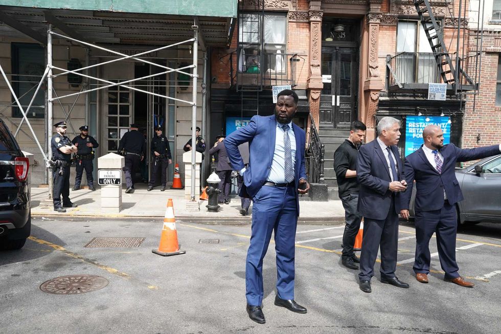 Police officers stand outside the 9th Precinct, where the suspect for yesterday