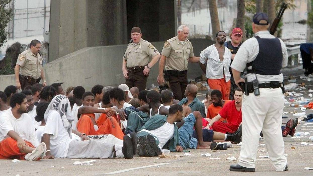 Police watch over prisoners from Orleans Parish Prison who were evacuated from their prison to the highway due to high water September 1, 2005 in New Orleans, Louisiana. Rescue efforts continue as officials in New Orleans fear the death toll from Hurricane Katrina could be in the thousands. (Photo by Mario Tama/Getty Images)