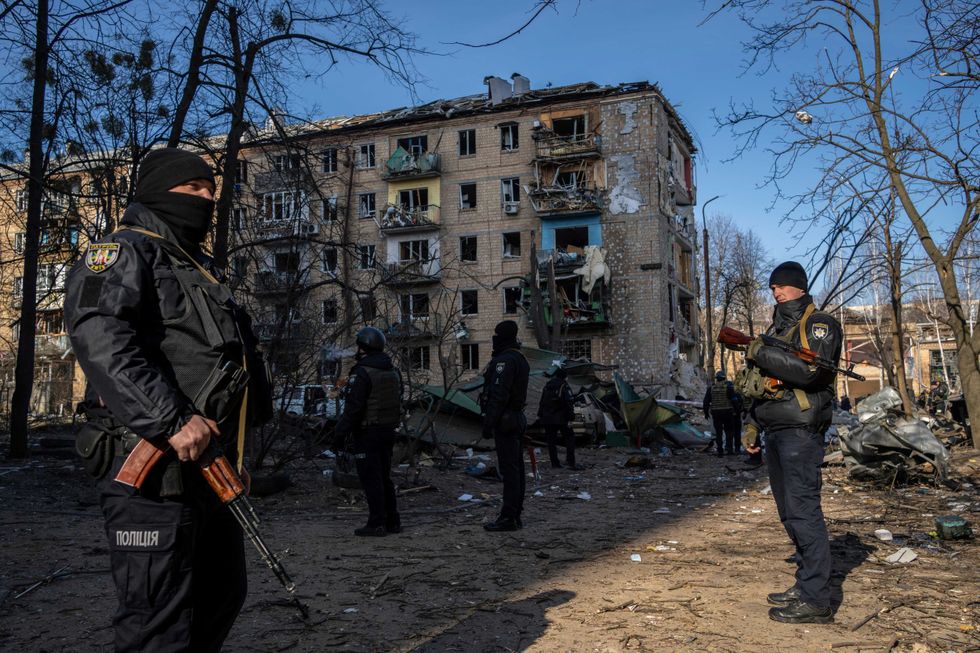 Policemen stand guard at the site where a bombing damaged residential buildings in Kyiv, Ukraine, Friday, March 18, 2022
