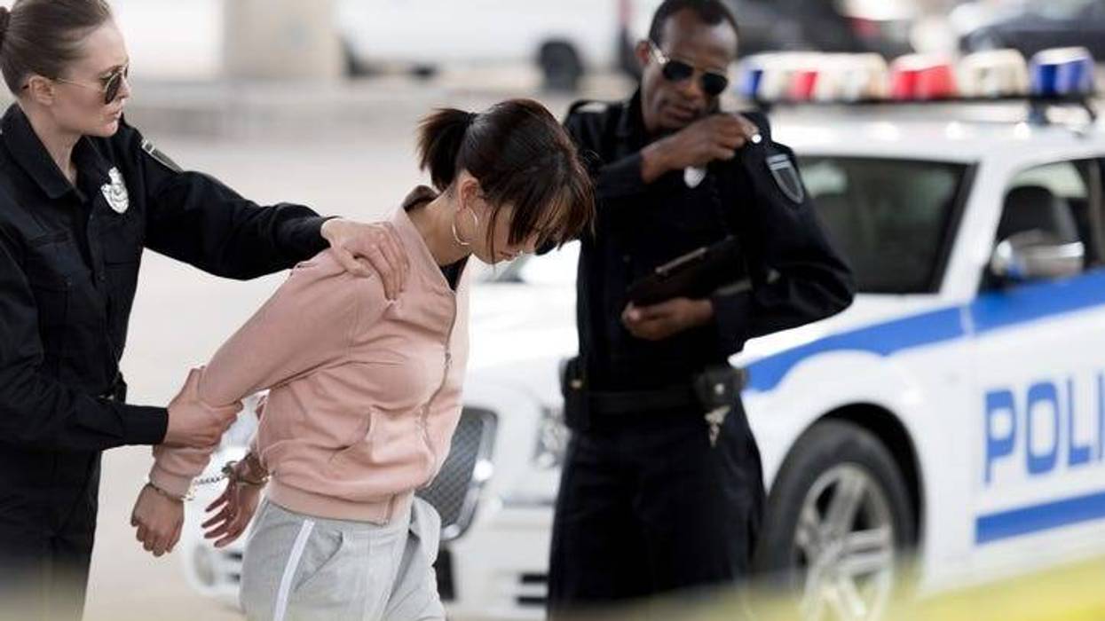 policewoman holding arrested young woman while her partner talking on portable radio