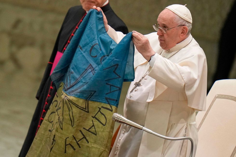 Pope Francis raises a Ukrainian flag brought to him from Bucha, Ukraine, at the Vatican on Wednesday, April 6, 2022