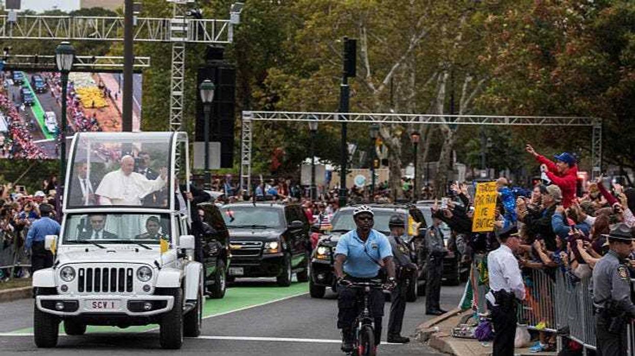 Pope Francis waves to the crowd while traveling along the Benjamin Franklin Parkway to conduct Mass and meet with organizers, volunteers and benefactors of the World Meeting of Families in Philadelphia, on Sept. 27, 2015.