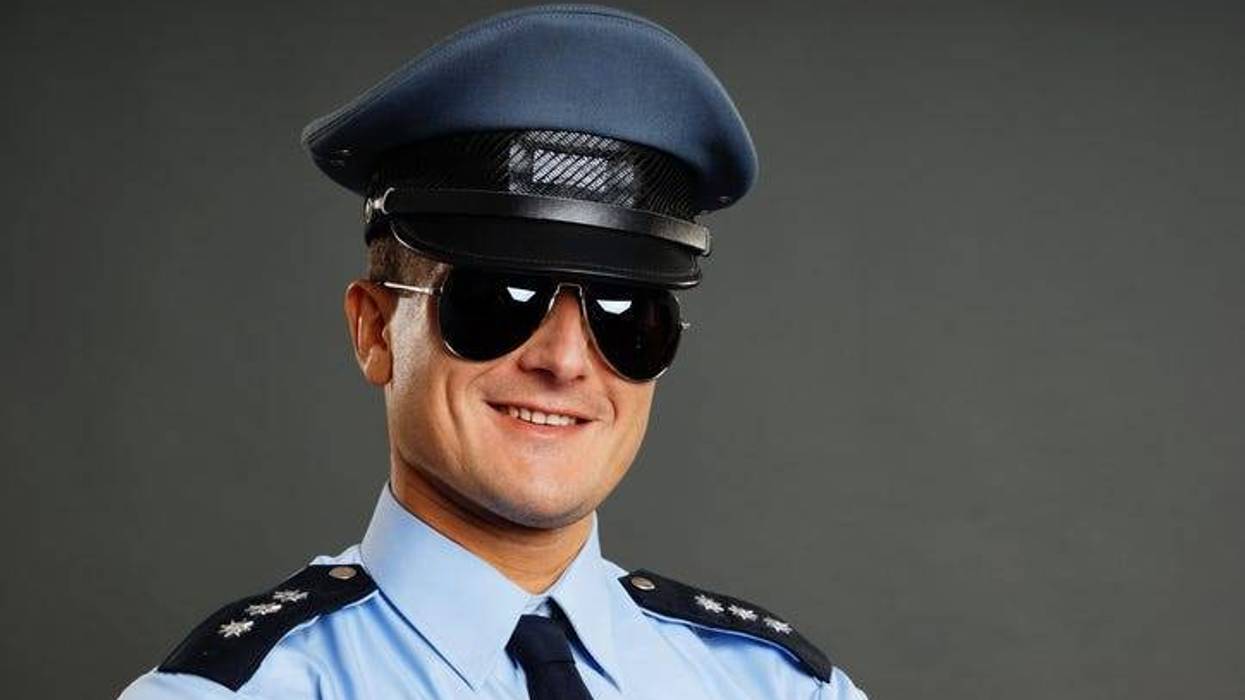 Portrait of smiling policeman in sunglasses on the gray background