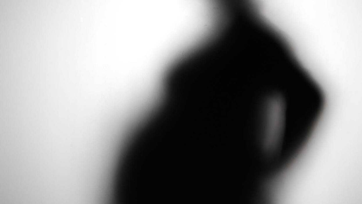 Pregnant woman silhouette, blurred. Stock photo.