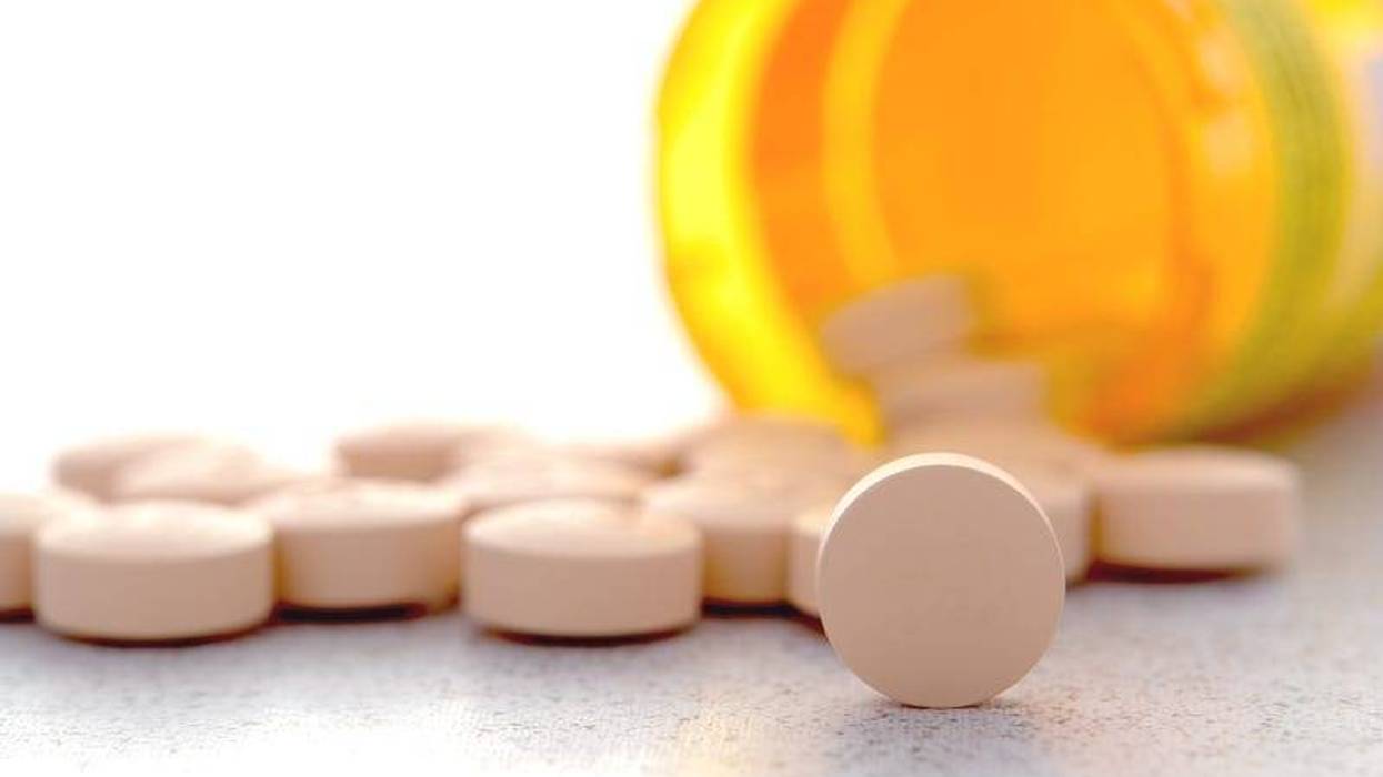 Prescription pain RX medication pills spilled out of an amber pharmacy medicine bottle on a pharmacy counter