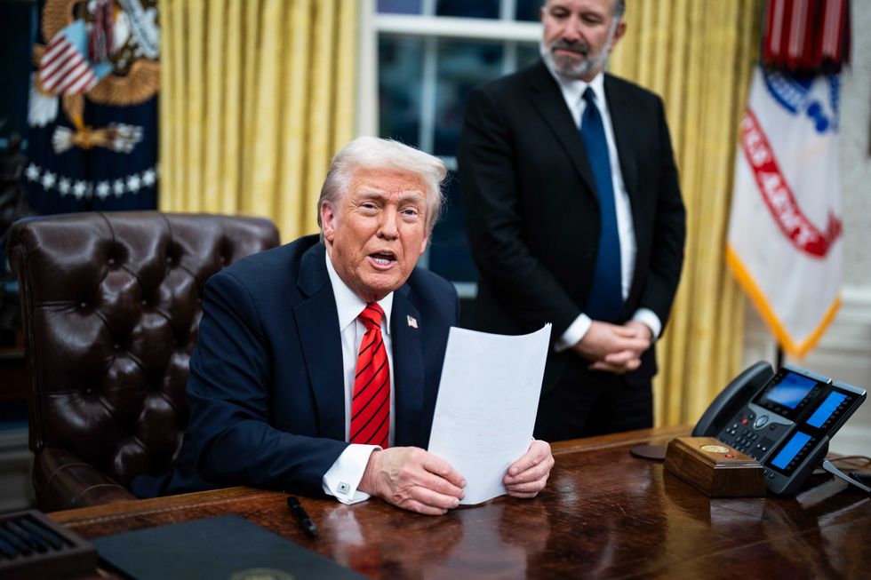 President Donald Trump, flanked by Commerce Secretary nominee Howard Lutnick, speaks with reporters and signs executive orders in the Oval Office at the White House on Feb. 10, 2025