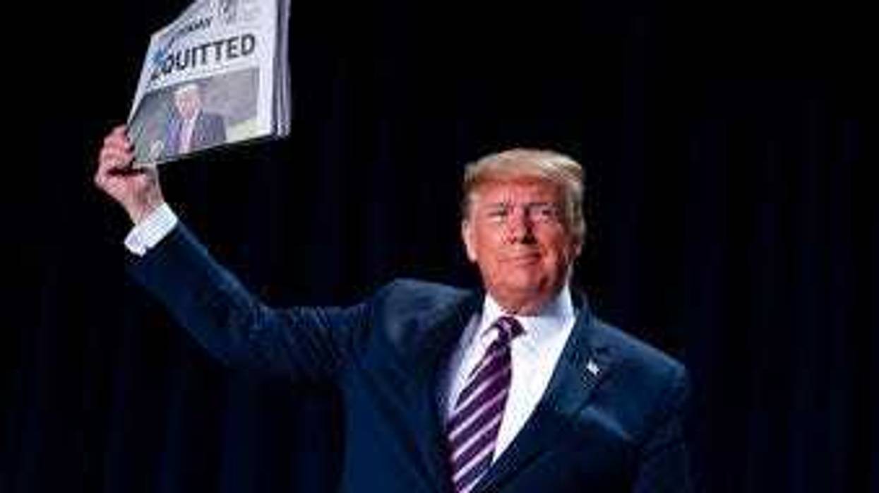 President Donald Trump holds up a newspaper with a headline that reads "ACQUITTED" during the 68th annual National Prayer Breakfast, at the Washington Hilton, Thursday, Feb. 6, 2020, in Washington. (AP Photo/ Evan Vucci)