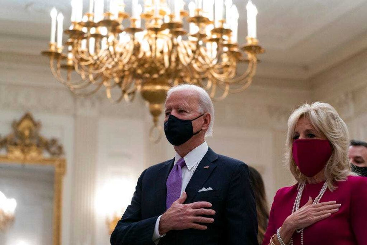 President Joe Biden, accompanied by first lady Jill Biden, places his hand over his heart during a performance of the national anthem, during a virtual Presidential Inaugural Prayer Service. (AP Photo/Alex Brandon)