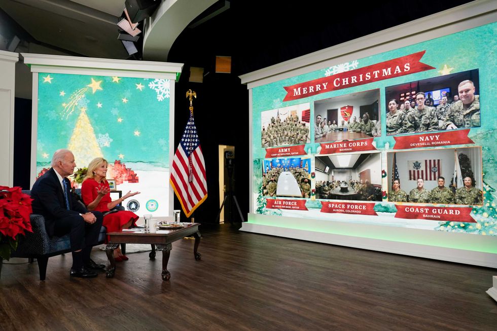 President Joe Biden, first lady Jill Biden and their new dog Commander, a purebred German shepherd puppy, meet virtually with service members around the world, Saturday, Dec. 25, 2021, in the South Court Auditorium on the White House campus in Washington, to thank them for their service and wish them a Merry Christmas