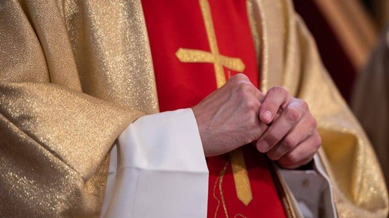 Priest in cassock while holding hands together