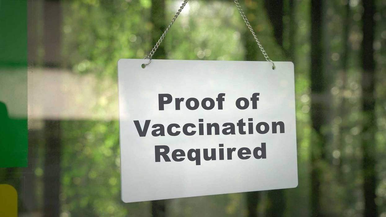 Proof of Vaccination Required sign hanging on the door front of a shop