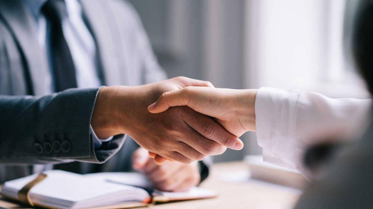 Prospective employee shakes hands with potential employer at a job interview.