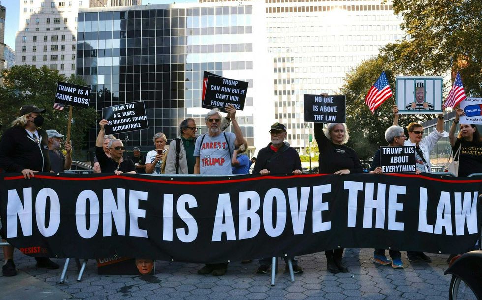 Protesters hold banners before the arrival of Donald Trump to New York State Supreme Court on Oct. 2, 2023