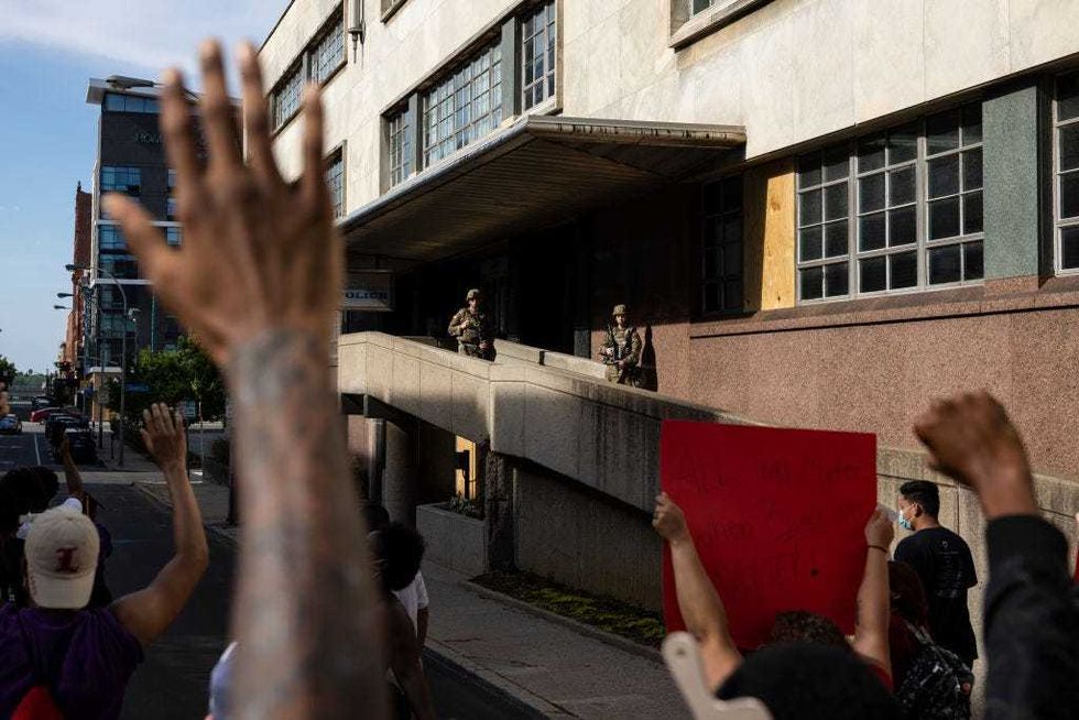 Protesters march through downtown past a government building guarded by members of the national guard on June 5, 2020 in Louisville, Kentucky.