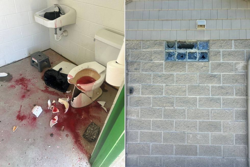 Public restroom vandalized: broken toilet, red substance on floor. Exterior wall: smashed glass block window.