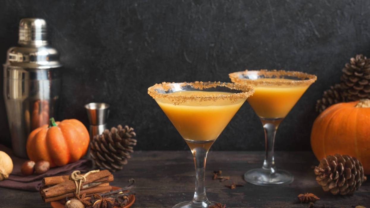 Pumpkintini. Pumpkin martini cocktail, homemade festive seasonal drink for Thanksgiving and Halloween party. Pumpkin pie spice cocktail and autumn decor.