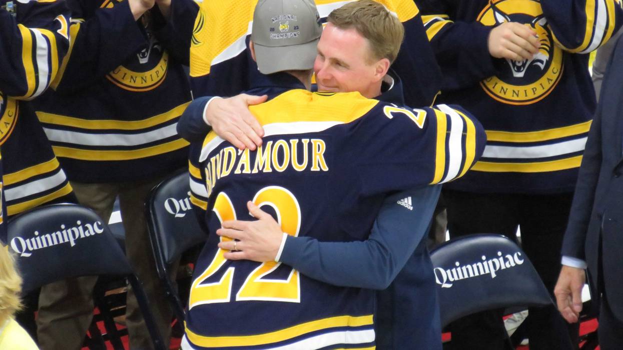 Quinnipiac men's hockey coach Rand Pecknold greets senior center Skyler Brind'Amour at the Bobcats' national championship celebration in Hamden, 4/10/23