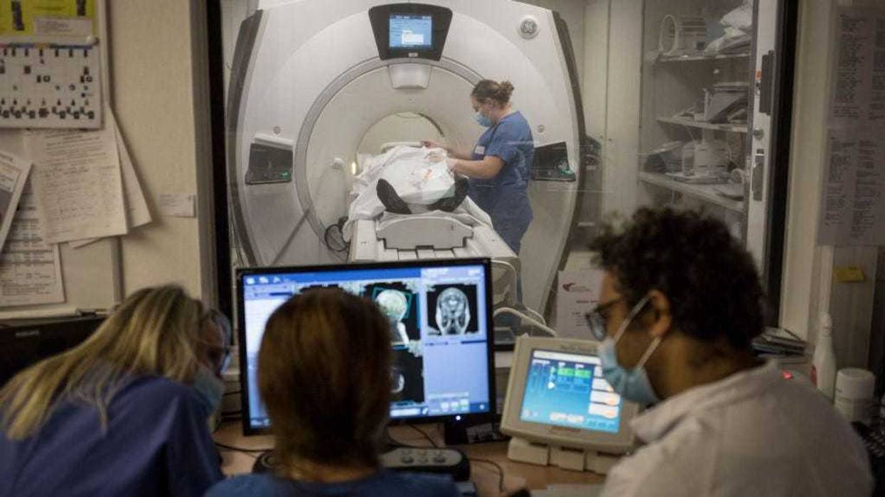 Radiologist Arshid Azarine (R) consults with a medical team as they conduct an MRI scan on a patient at the Paris Saint-Joseph hospital on October 29, 2020 in Paris, France.