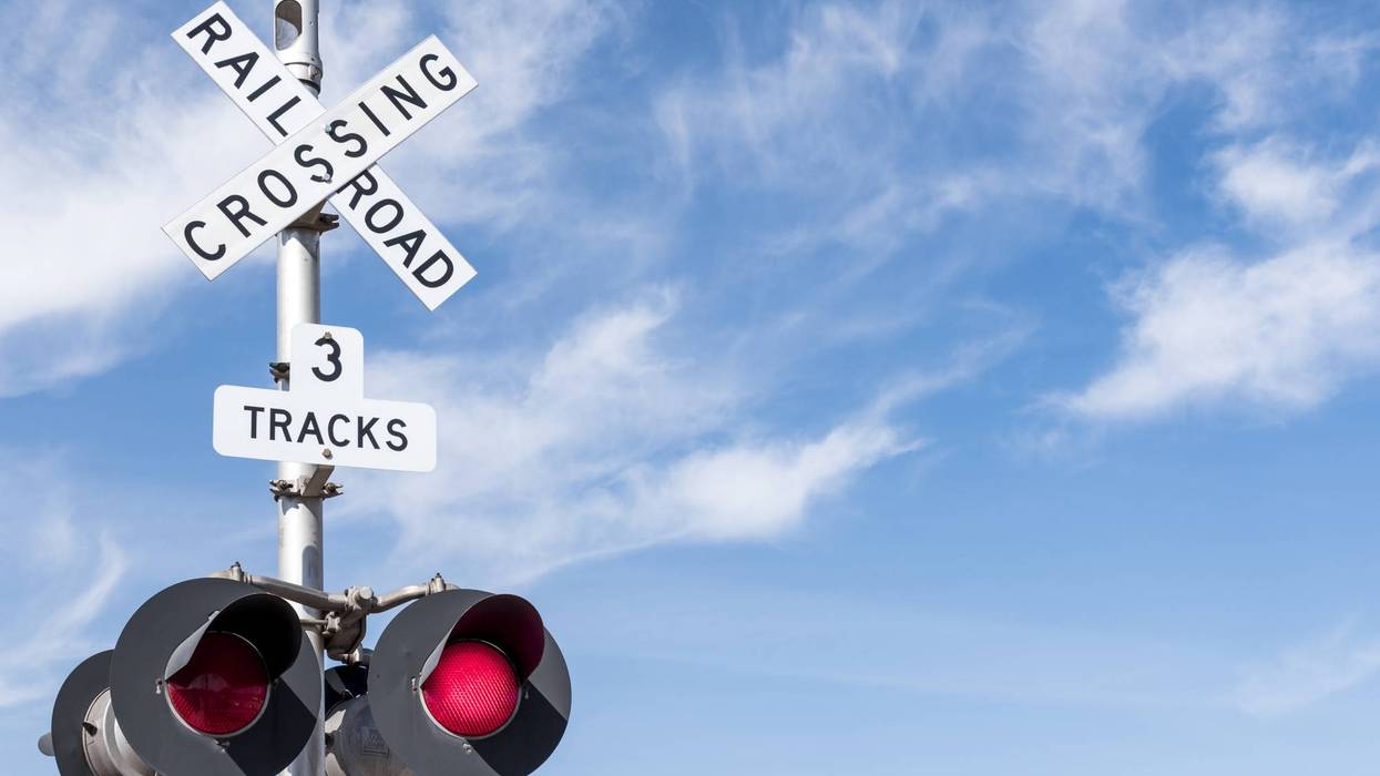 Railroad Crossing with Wispy Cloud in Blue Sky behind