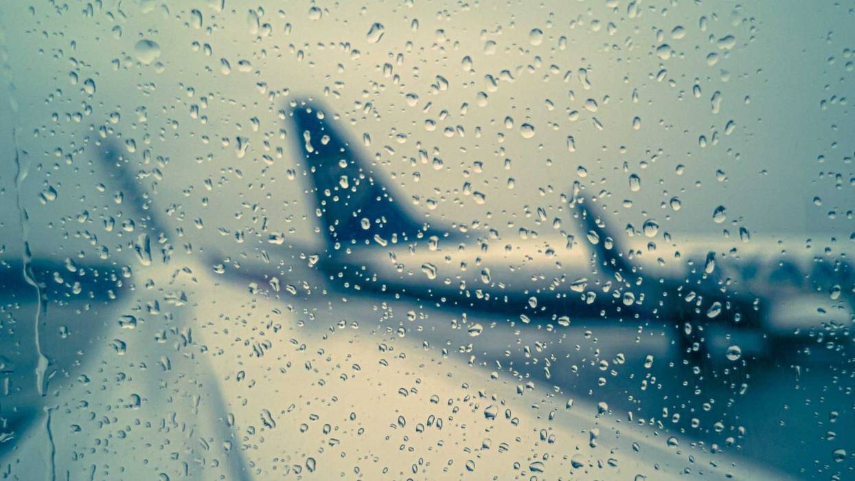 Raindrops on the glass against the background of a wing and a standing plane