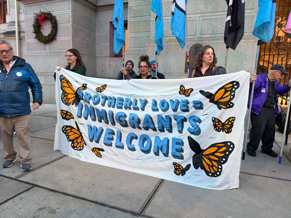 Rally-goers at City Hall hold a banner welcoming immigrants to Philadelphia.