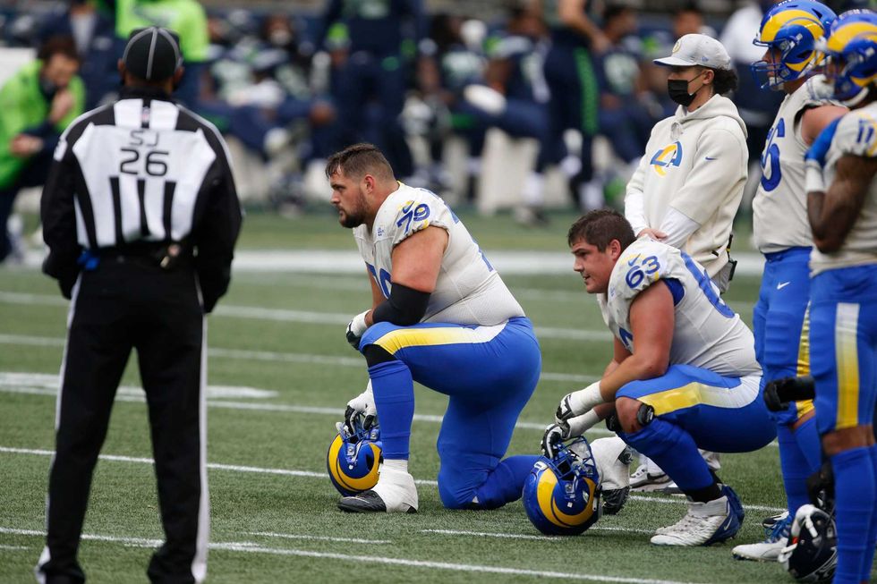 Rams offensive linemen Rob Havenstein and Austin Corbett kneel and look on as Wolford gets evaluated.
