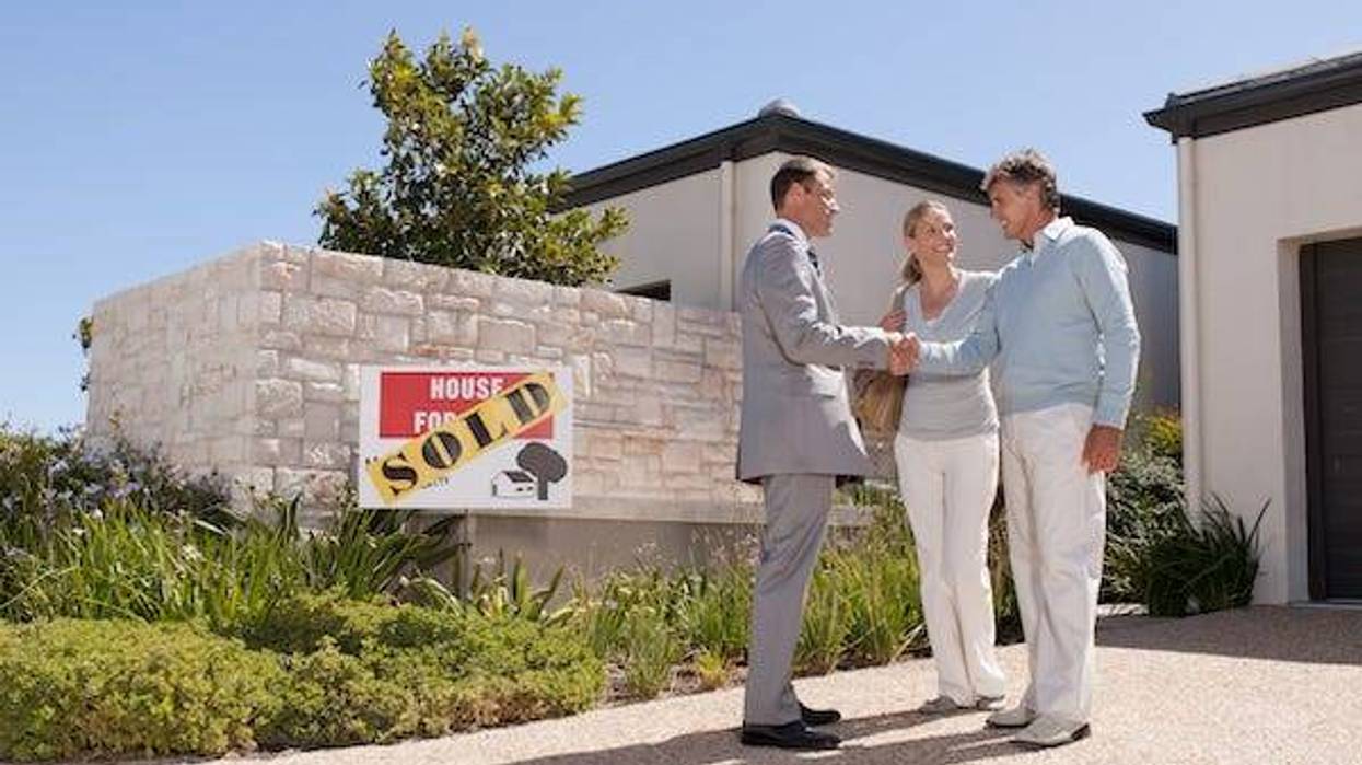Real estate agent shaking hands with couple at new home