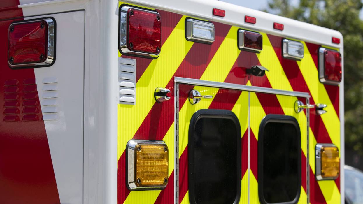 Rear of an ambulance with red and yellow chevron reflective stripes and emergency lights.