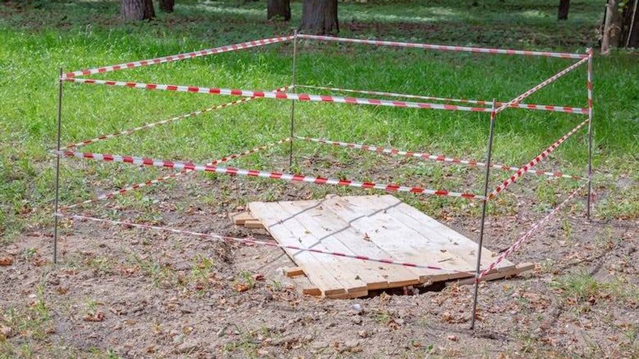 Red and white police tape in the city park. Sinkhole warning
