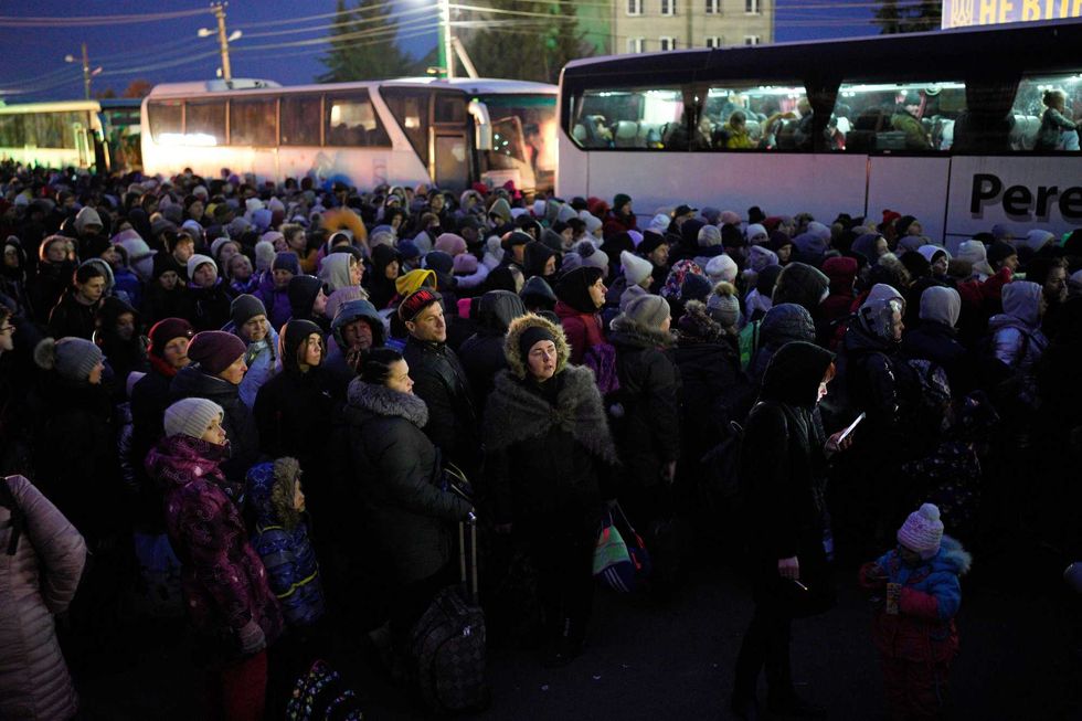 Refugees fleeing the war in Ukraine, form a line as they approach the border with Poland in Shehyni, Ukraine, Sunday, March 6, 2022