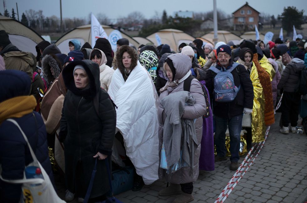 Refugees wait in a crowd for transportation after fleeing from the Ukraine and arriving at the border crossing in Medyka, Poland, Monday, March 7, 2022