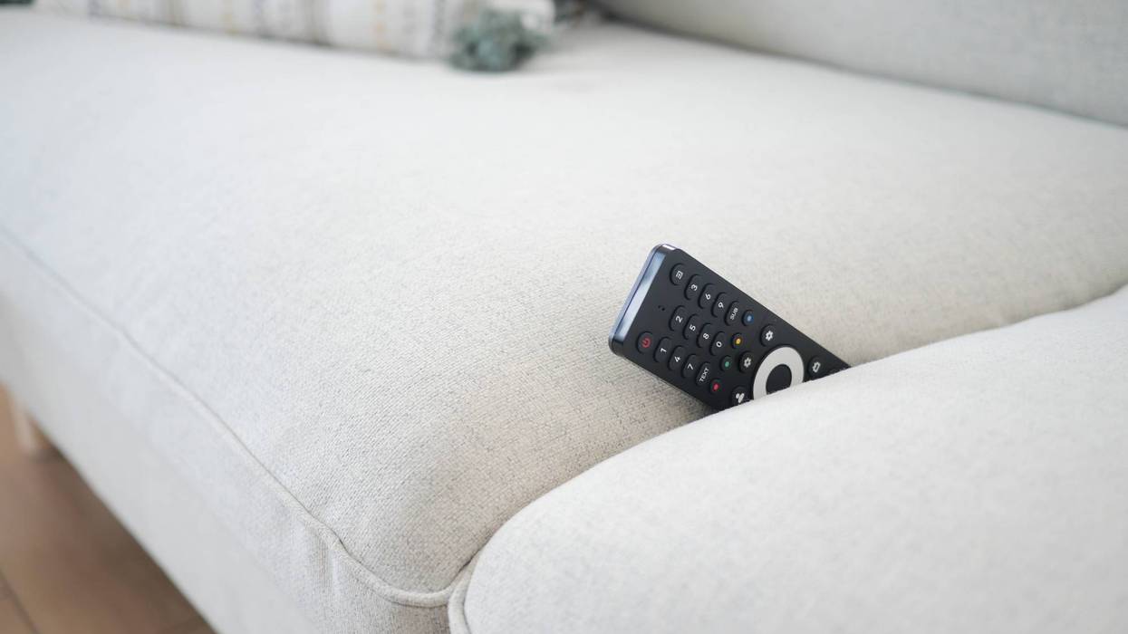 Remote control on a light gray sofa cushion. lost remove control concept