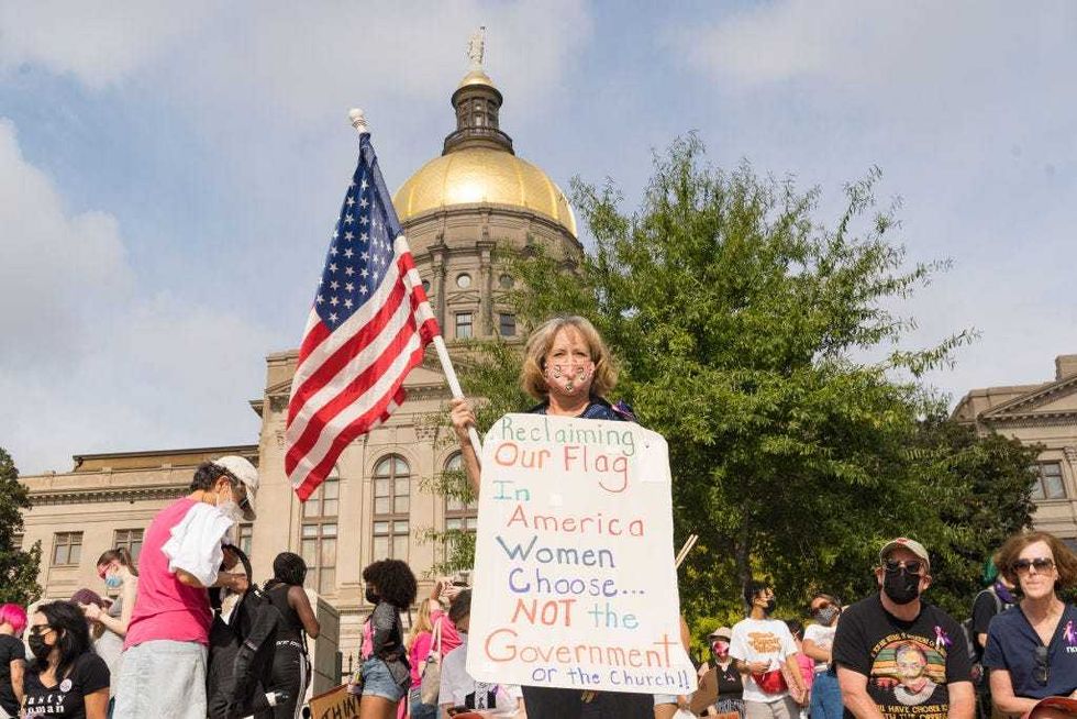 Renee Bates holds a flag and a sign as demonstrators rally in support of women
