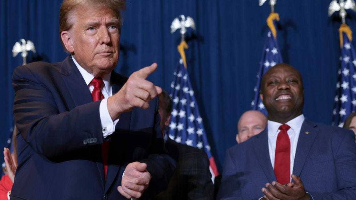 Republican presidential candidate and former President Donald Trump gestures to supporters as Sen. Tim Scott (R-SC) looks on during an election night watch party at the State Fairgrounds on February 24, 2024 in Columbia, South Carolina. Trump defeated Republican presidential candidate, former U.N. Ambassador Nikki Haley in her home state as South Carolina held its primary today.