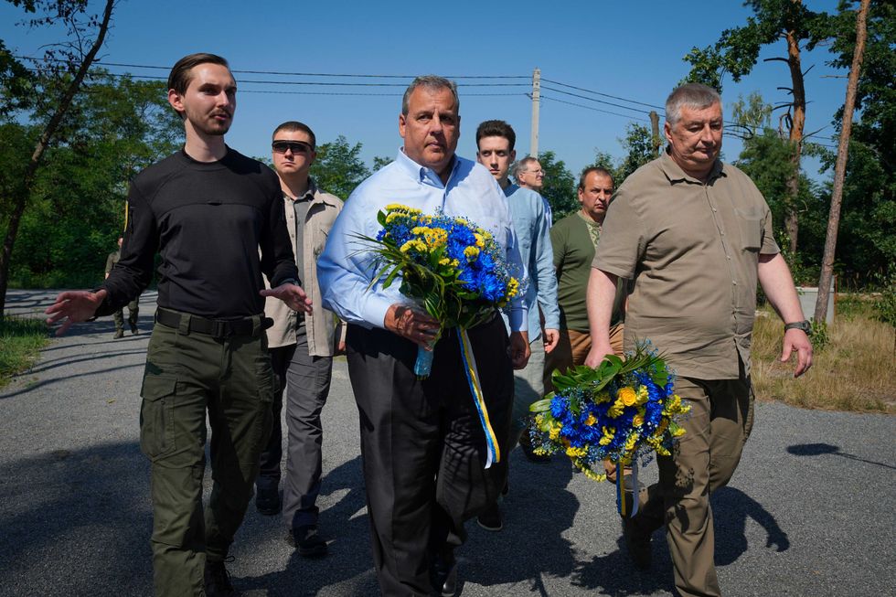 Republican presidential candidate former New Jersey Gov. Chris Christie, centre, participates in a flowers laying ceremony as he visits a former defence line from Russian massive offensive in March 2022 in the village of Moshchun, outskirts of Kyiv, Ukraine, Friday, Aug. 4, 2023