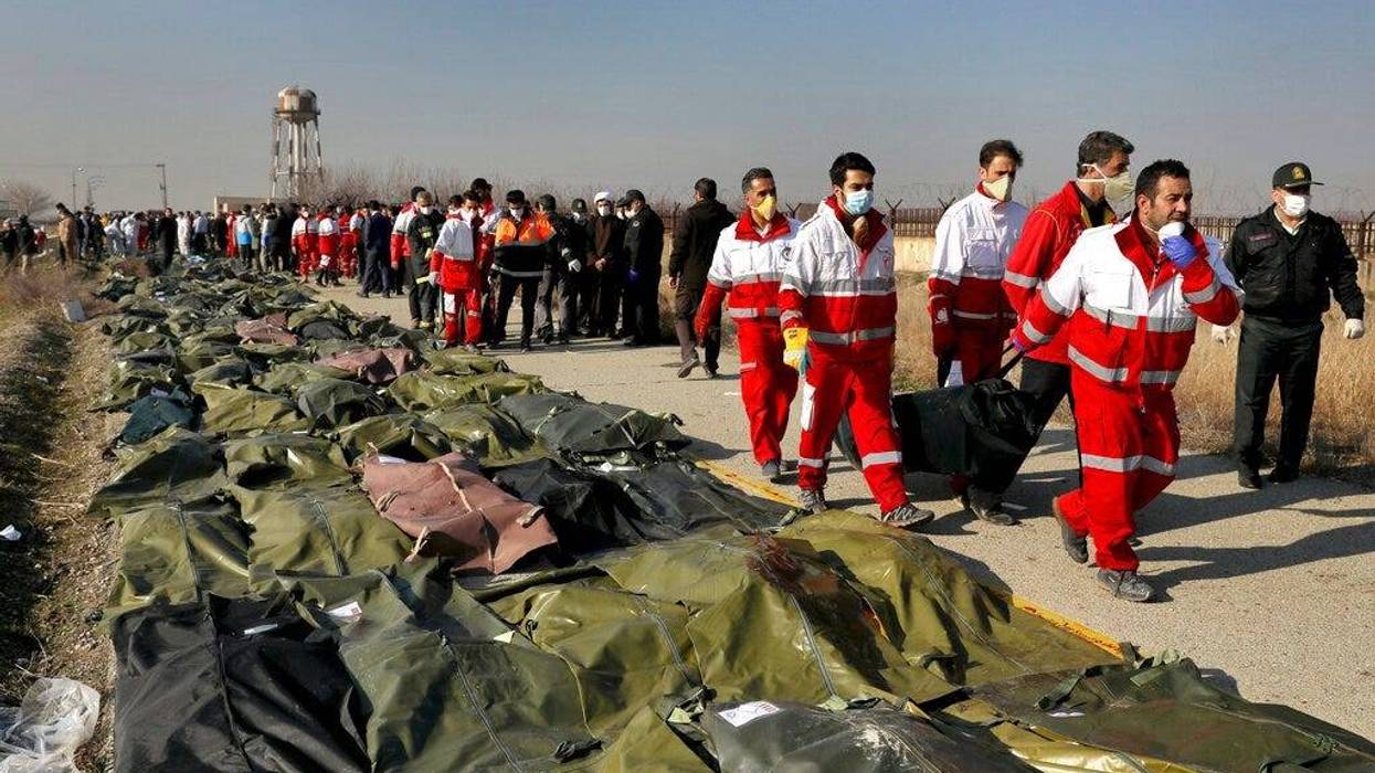 Rescue workers carry the body of a victim of a Ukrainian plane crash in Shahedshahr, southwest of the capital Tehran, Iran