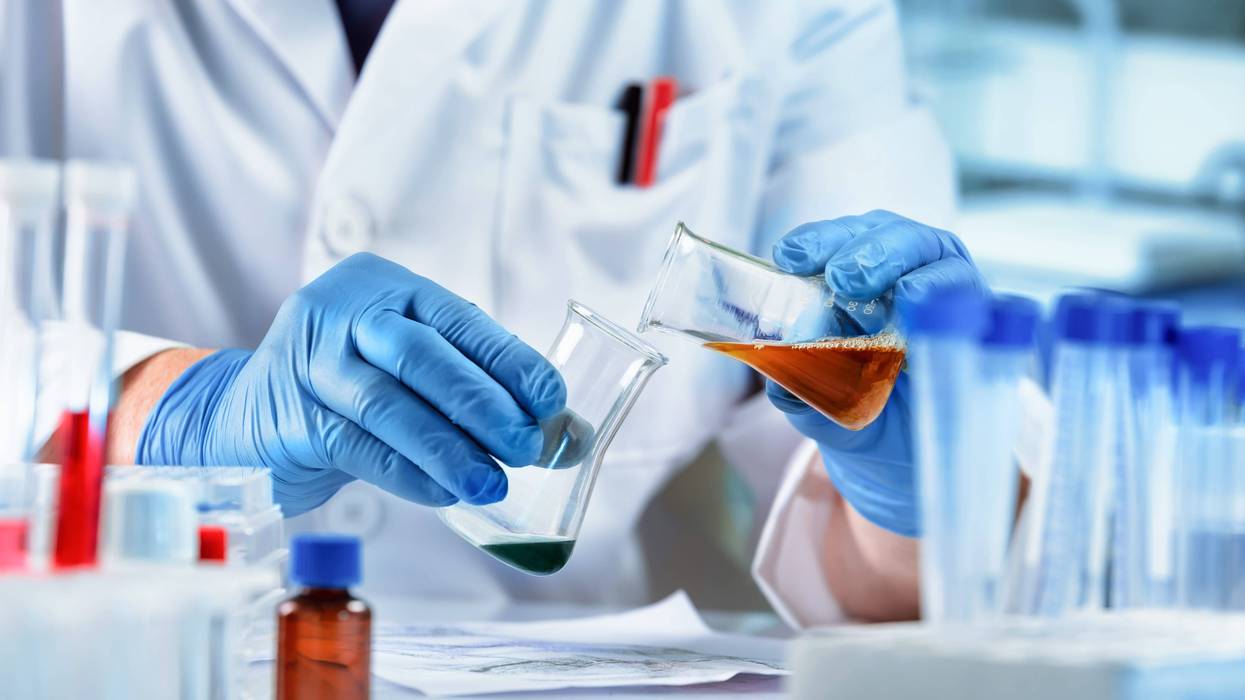 Researcher working with fluids in flasks in a laboratory