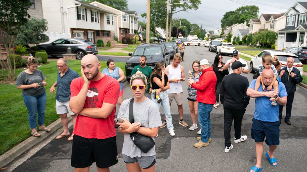 Residents gather near the home being searched by police in Massapequa Park on July 14, 2023