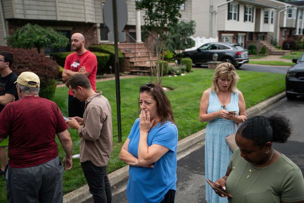 Residents try to take a look as police officers search the house where a suspect has been taken into custody on New York