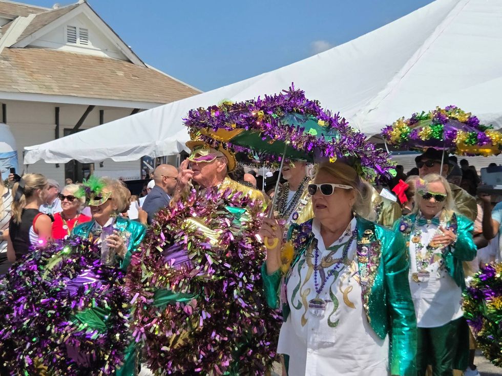 Revelers in purple, green and gold welcome the train to Gulfport, MS