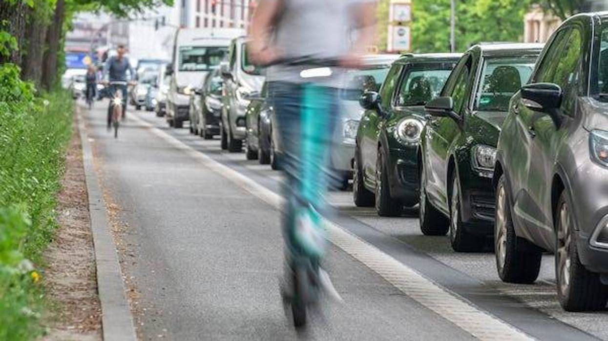 Riding electric scooters in bike lane past traffic jam