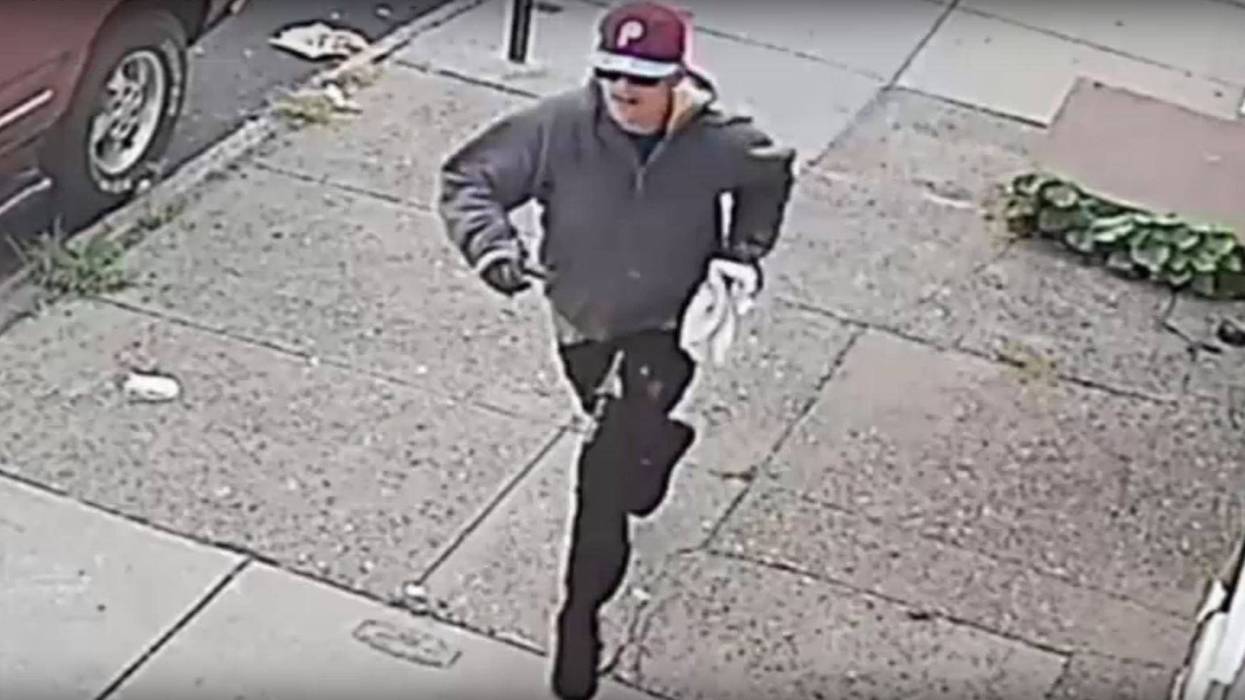 Robbery suspect wearing gloves, sunglasses and a burgundy Phillies cap.