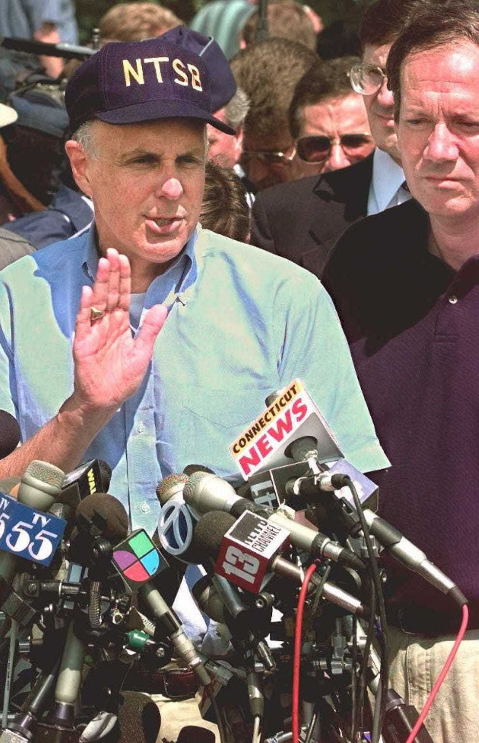 Robert Francis, (L) Then-Vice Chairman of the US National Transportation Safety Board (NTSB) speaks to the press July 18, 1996 in East Moriches, New York. Francis updated the press on rescue operations for the TWA flight 800. Then-New York Governor George Pataki is on the right.